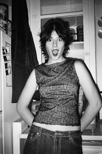 a black and white photo of a woman posing in a kitchen