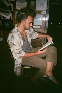 a man sitting on a chair reading a book