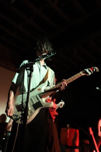 a man playing a guitar in front of a microphone